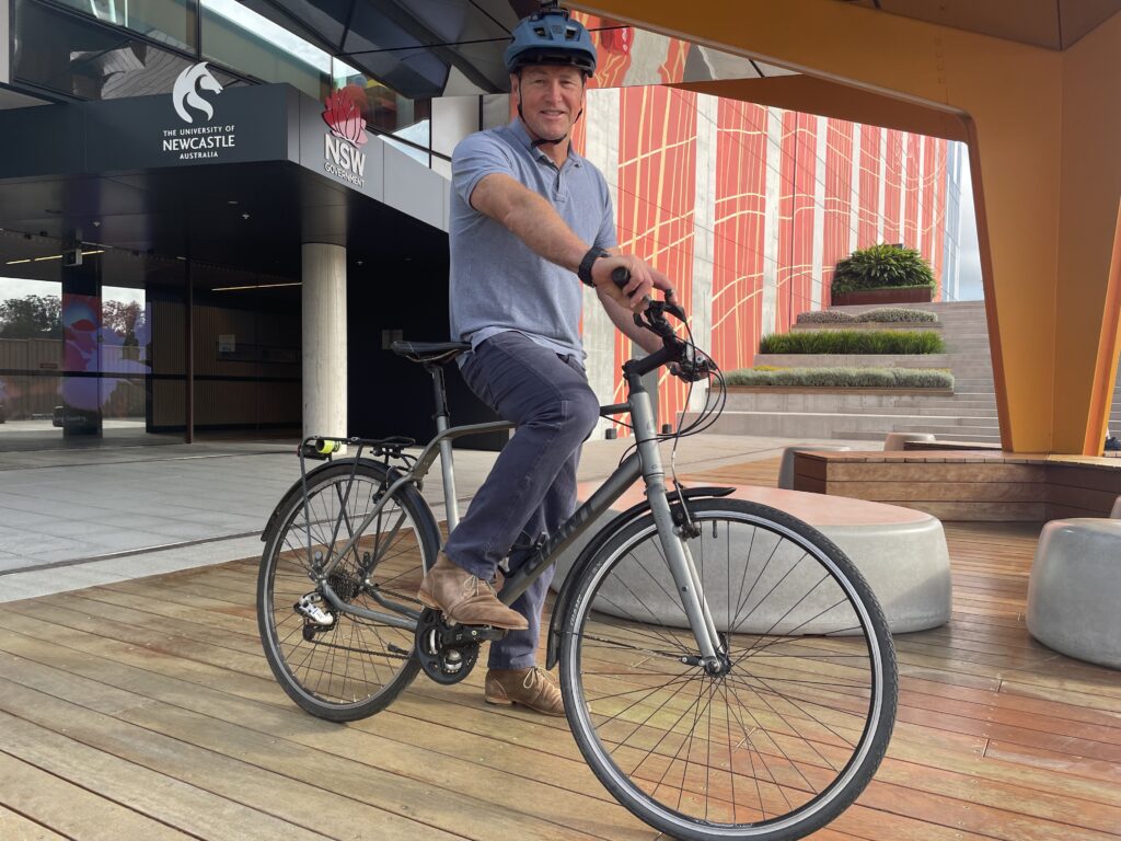 Nigel Tebb on his bicycle outside the Central Coast Clinical School and Research Institute building.