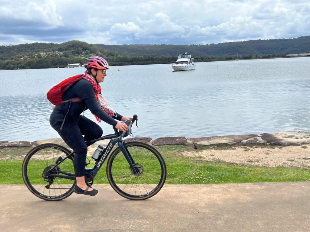 Yoni Hope-Hodgetts cycling along a pathway in front of Gosford waterfront.