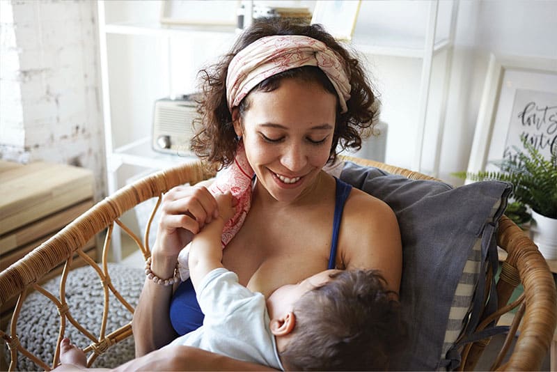 A woman at home breastfeeding.