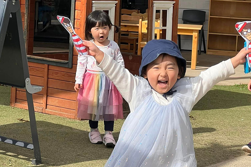 Two Asian children playing outside in an early childhood centre.