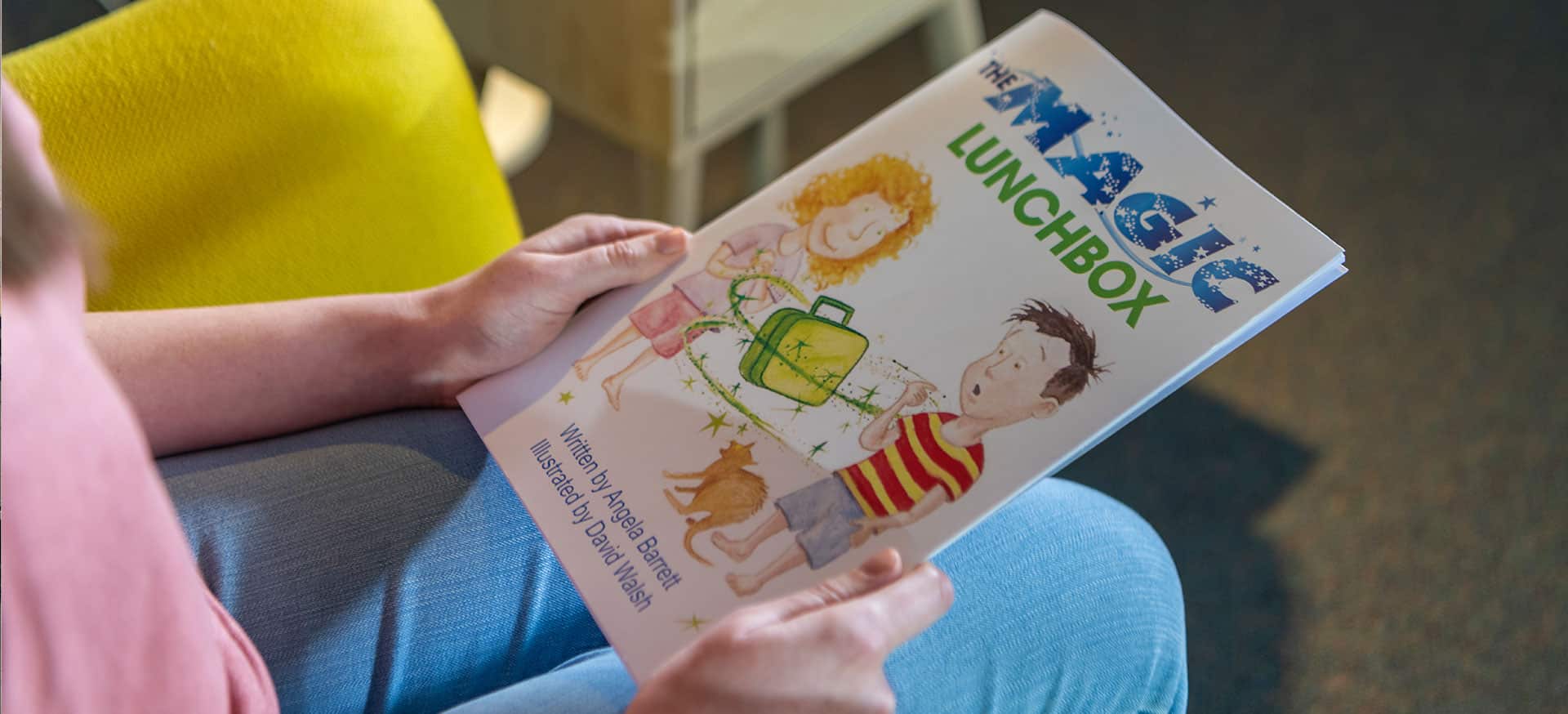 Two adult hands preparing to read The Magic Lunchbox book.