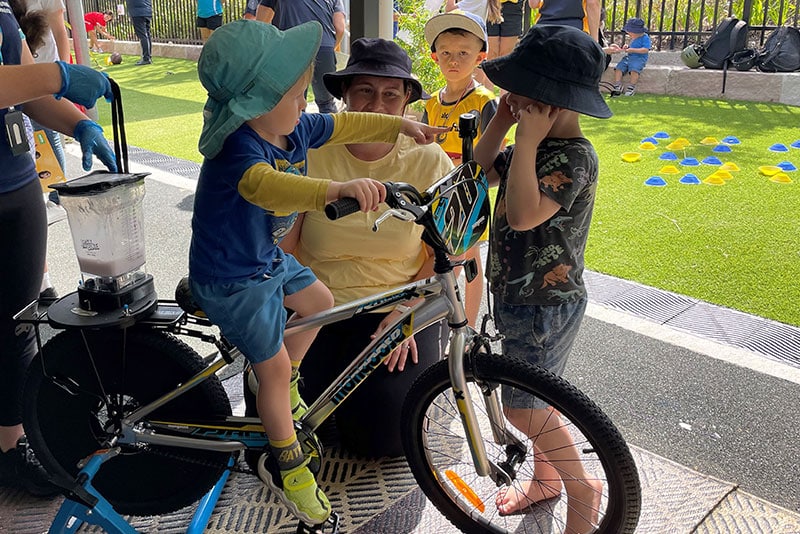 Young children at an early childhood centre a Blender Bike making a smoothie.