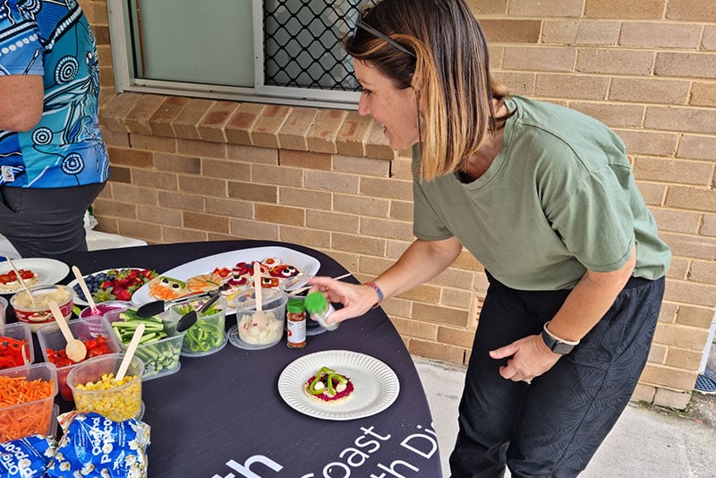 An assortment of healthy food on a table at a PDHPE Network meeting event with one participant filling their plate.