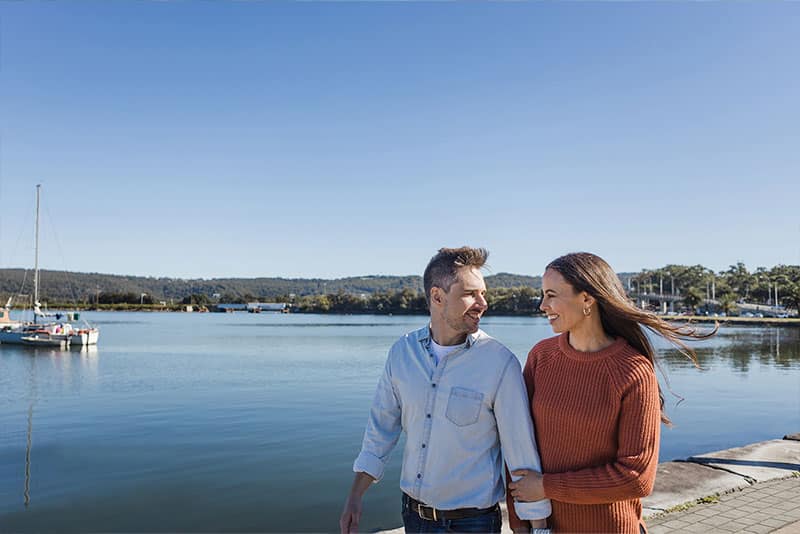 A man and woman walking along Gosford waterfront.