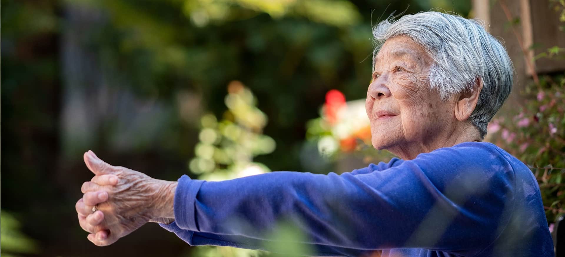 An older lady doing balance exercises outside.