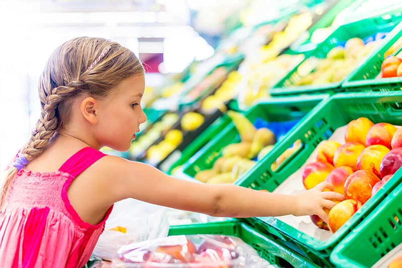 A girl picking out fruit at the supermarket.