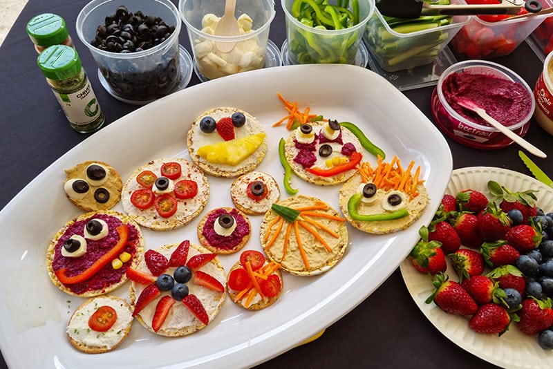 A platter of fruit and vegetables made into smiley faces.