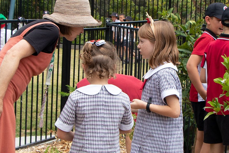 School children showing off vegetables to a teacher.