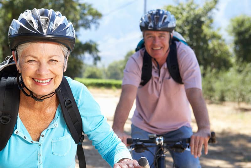 Two older adults cycling.