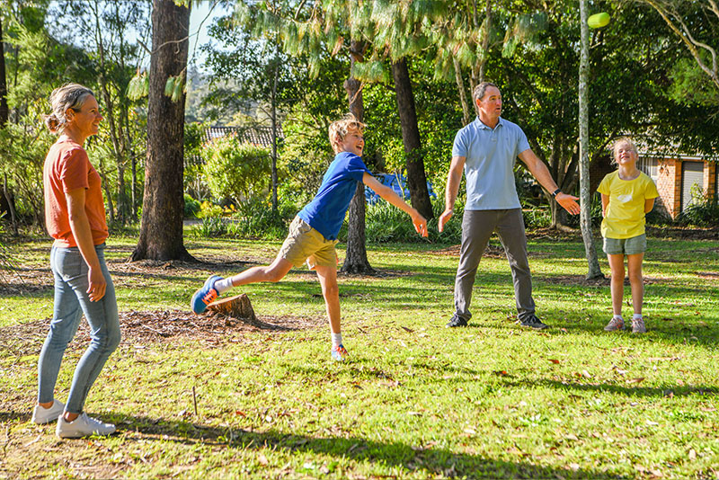 A family playing on fo the Family ACTIVstion games with a young boy throwing a tennis ball as the mother, daughter and father look on.