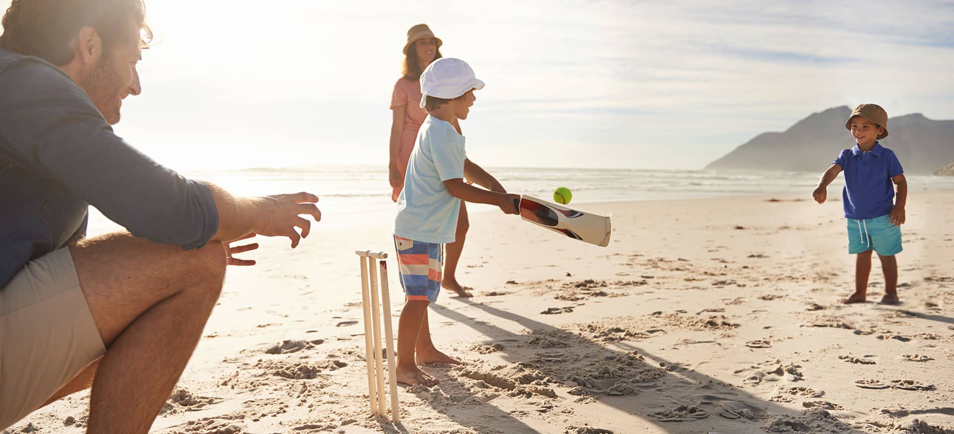 A family playing cricket on a beach.