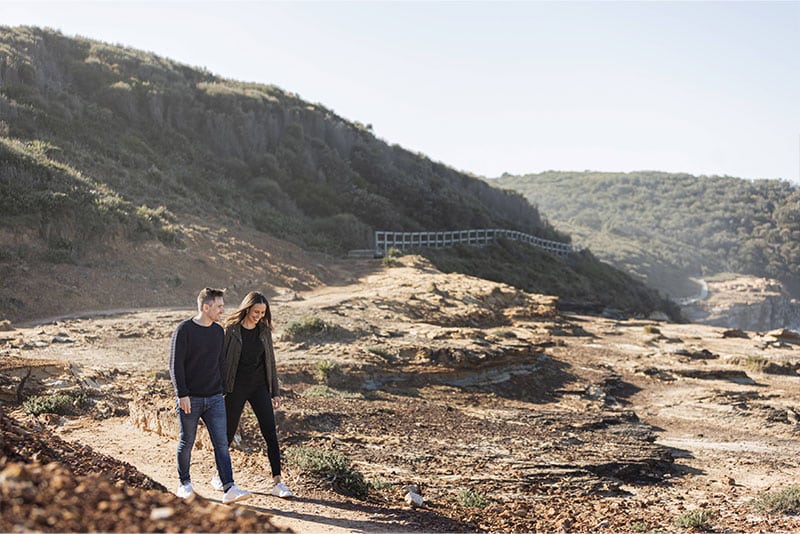 A young couple walking along Bouddi National Park.