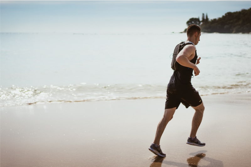A young man jogging along a beach.