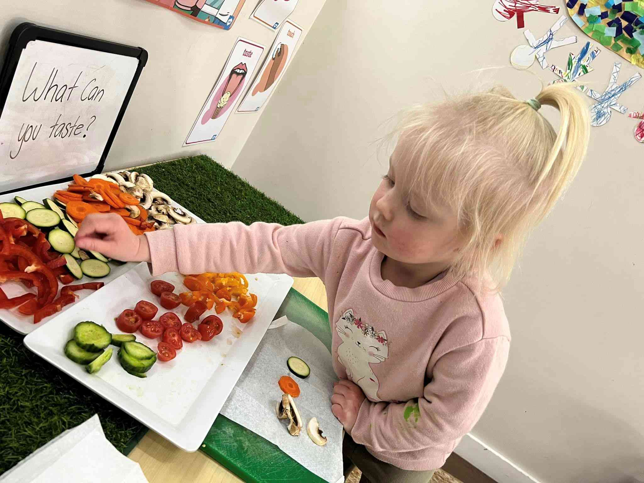 A child at an early childhood service taste testing different fruit and vegetables.