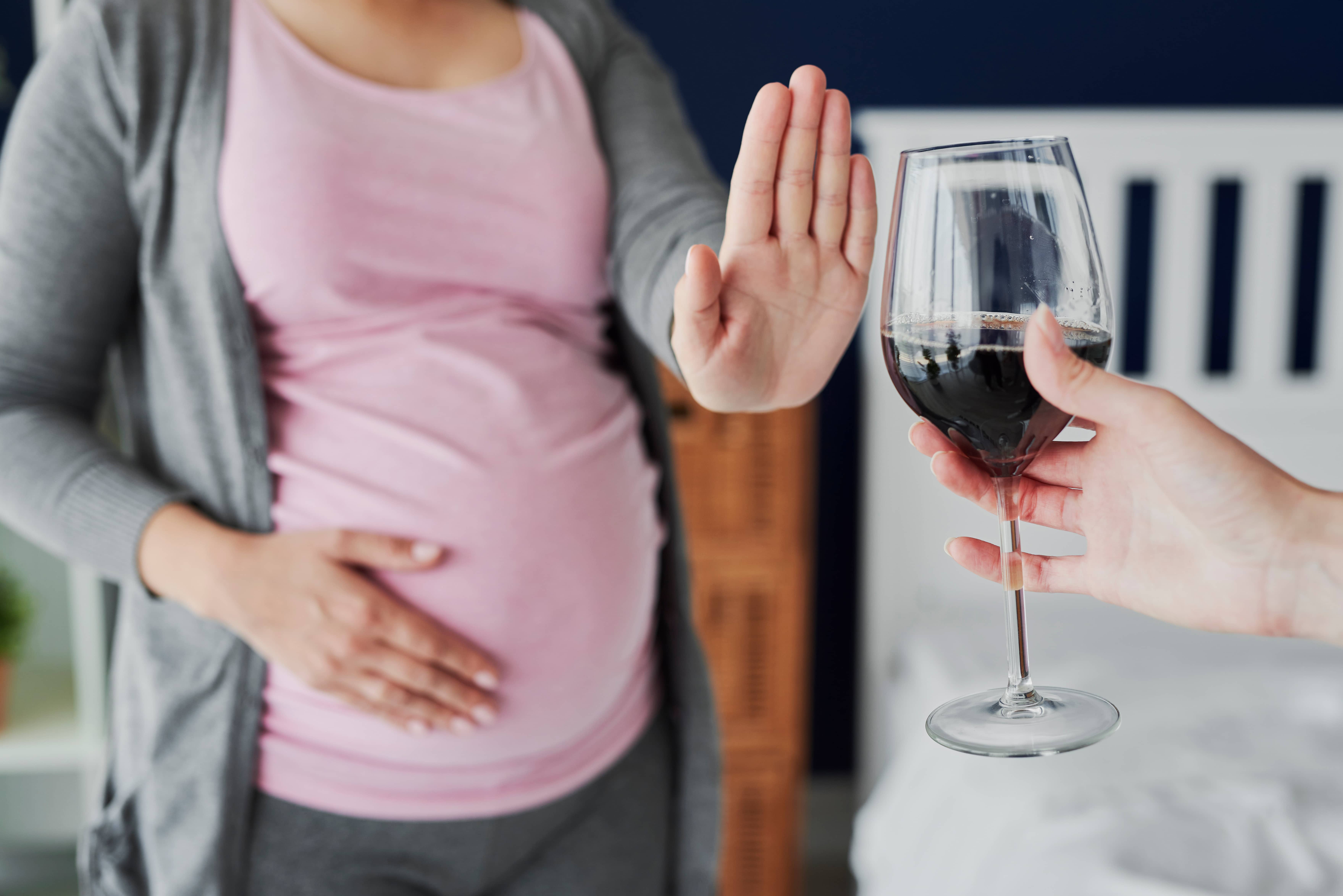 Pregnant woman refusing a glass of wine.