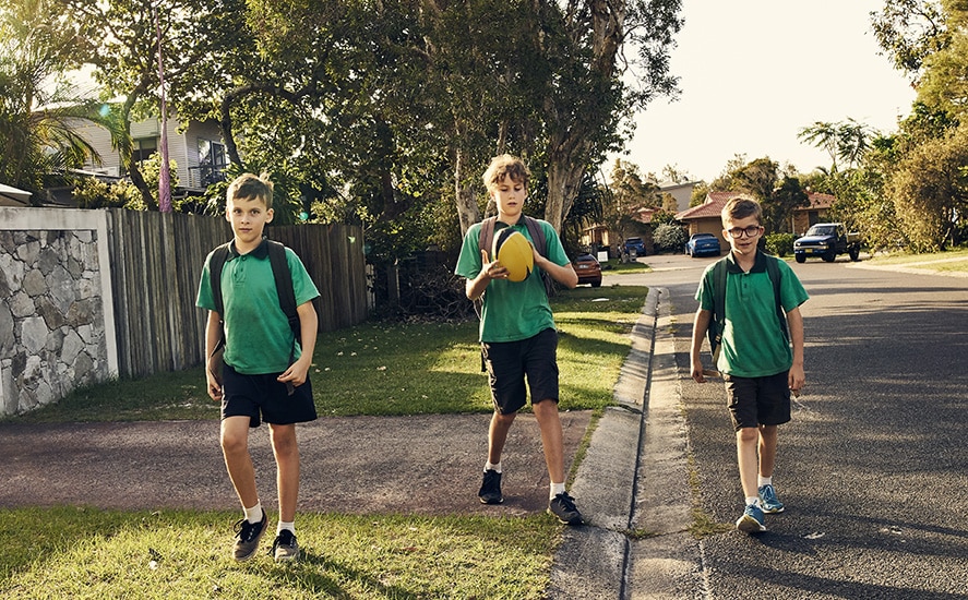 Shot of three boys walking in the street wearing school uniforms