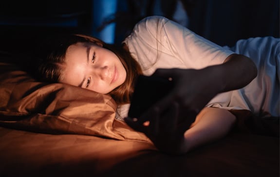 teenager girl on phone in bed at night